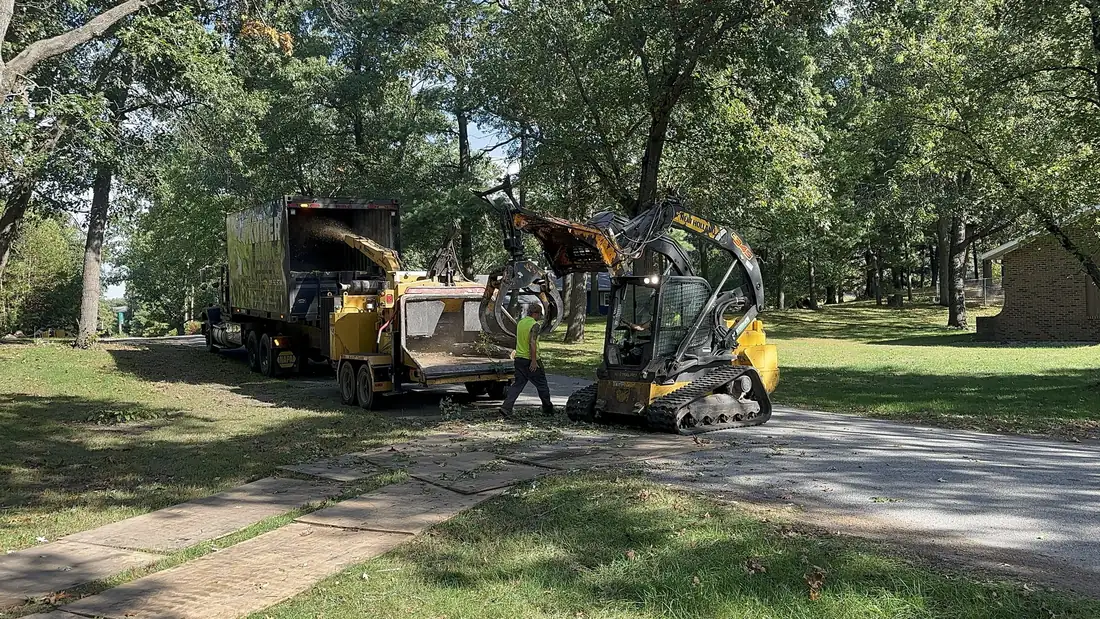 Grapple loading the chipper, mats protecting the lawn.